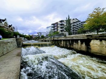 Built structure by river against sky