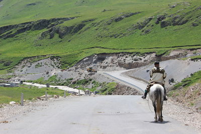 People riding motorcycle on road by mountain