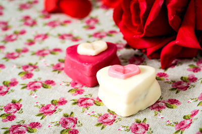 Close-up of heart shape desserts red rose on fabric