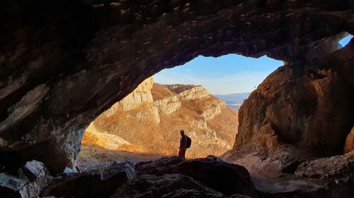 Man standing on rock by cave