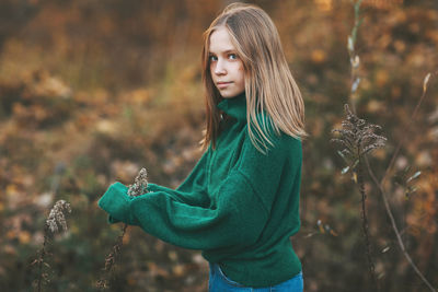 Portrait of a beautiful teenage girl with blond hair and blue eyes in an autumn park
