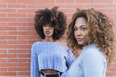 Portrait of woman with friend standing against wall