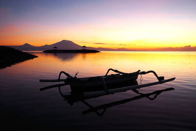 Silhouette boat in lake against sky during sunset