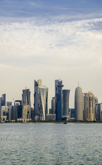 Sea by modern buildings against sky in city