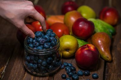 Close-up of hand holding berries with fruit on table