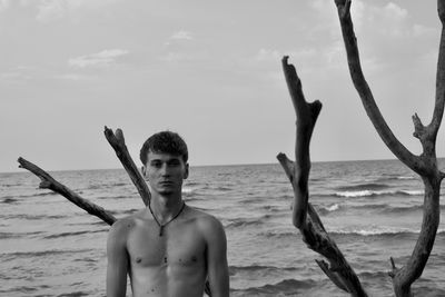 Portrait of shirtless man standing against sea