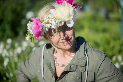 Portrait of smiling woman wearing flowers by field