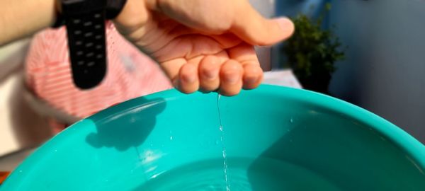 Close-up of water falling from hand in bucket