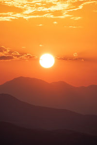 Scenic view of silhouette mountains against romantic sky at sunset