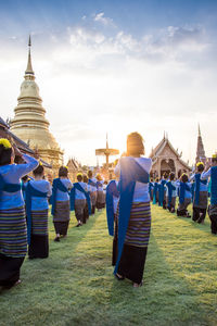 Women dancing in temple against cloudy sky on sunny day