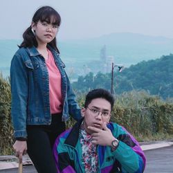 Portrait of young couple standing on mountain against sky