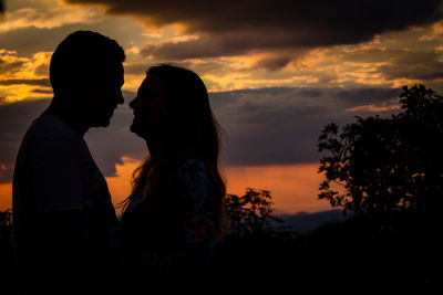Silhouette couple kissing against sky during sunset