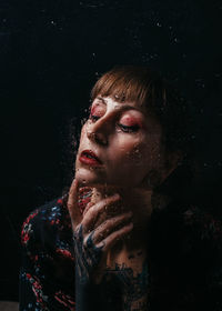 Portrait of young woman against black background