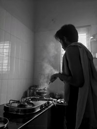 Side view of man preparing food in kitchen at home