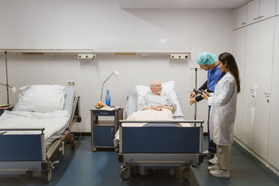 Smiling senior male patient looking at healthcare workers in hospital