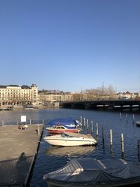 Sailboats moored in river against buildings in city