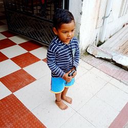 High angle view of boy looking down while standing on footpath