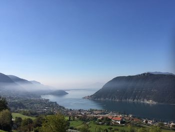 Scenic view of sea and mountains against clear blue sky