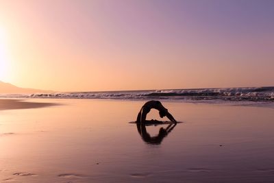 Silhouette person in sea against sky during sunset