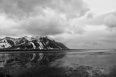 Scenic view of lake by snowcapped mountains against sky