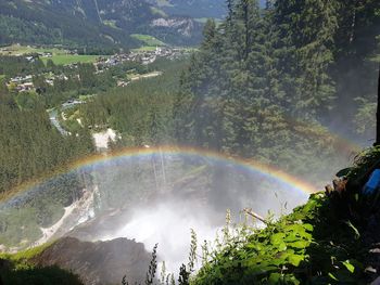 Scenic view of rainbow over trees and mountains