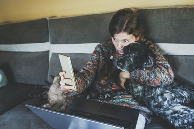 Woman taking selfie with dog at home