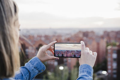 Midsection of woman photographing with mobile phone