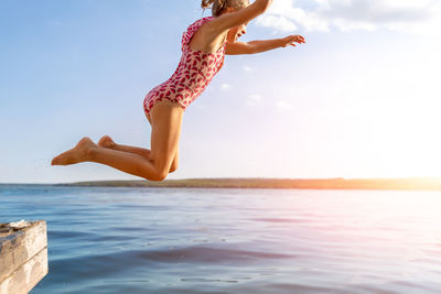 Man jumping in sea against sky