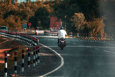 Rear view of people riding bicycle on road