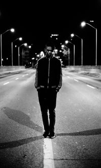 Man with umbrella standing on road at night