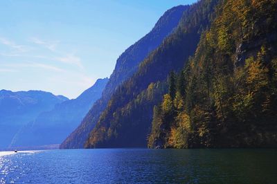 Scenic view of sea by mountain against sky