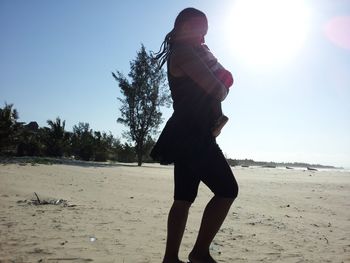 Side view of man standing on beach against sky