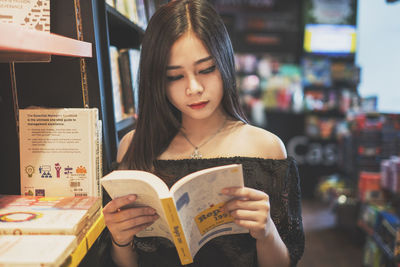 Young woman looking away while sitting on book