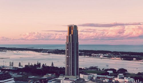 High angle view of factory by sea against sky during sunset