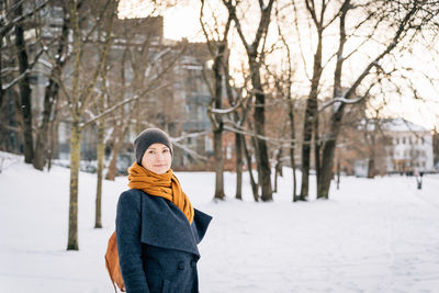 A woman on the street of a winter city looks into the camera
