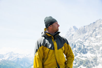 Young man standing by mountains against clear sky