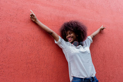 Happy woman standing against wall