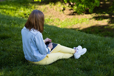 Low section of woman sitting on grassy field