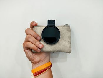 Close-up of hand holding camera against white background