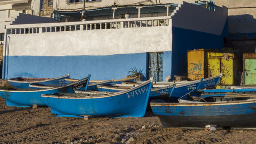 Boats moored on beach against buildings