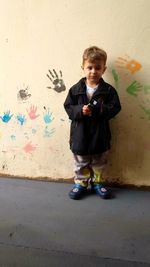 Full length of cute boy standing against wall