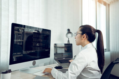 Side view of young woman working on computer in office