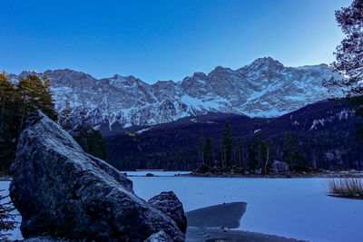 Scenic view of lake by mountains against clear blue sky