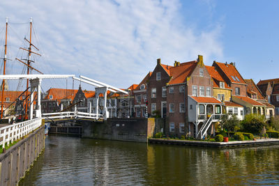 Bridge over river by buildings against sky