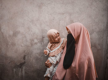 Rear view of couple standing against wall