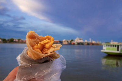 Close-up of food against lake during sunset