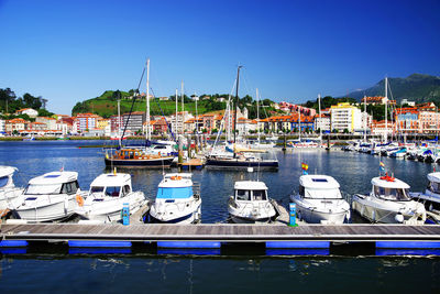 Sailboats moored at harbor against clear blue sky