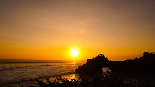 Scenic view of sea against sky during sunset in tanah lot, bali.