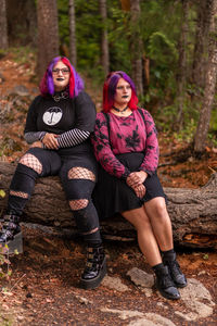 Low angle view of friends sitting in forest