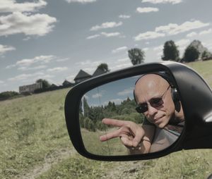 Reflection of man on side-view mirror of car